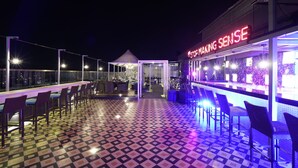 A rooftop bar with a checkered floor, bar seating, and a neon sign reading "STOP MAKING SENSE". - Brilliant Hotel & Convention Center (Indore)