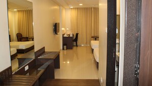 A hotel room with a bed, a desk, a chair, a mirror, and a small table. - Brilliant Hotel & Convention Center (Indore)