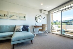 Relax in a spacious living room with a sofa, desk, and chair, offering a city view.