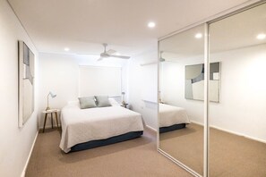 Relax in this serene bedroom with a large bed, bedside table, and ceiling fan.