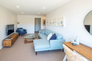 Relax in this stylish living room with a sofa, flat-screen TV, and book.