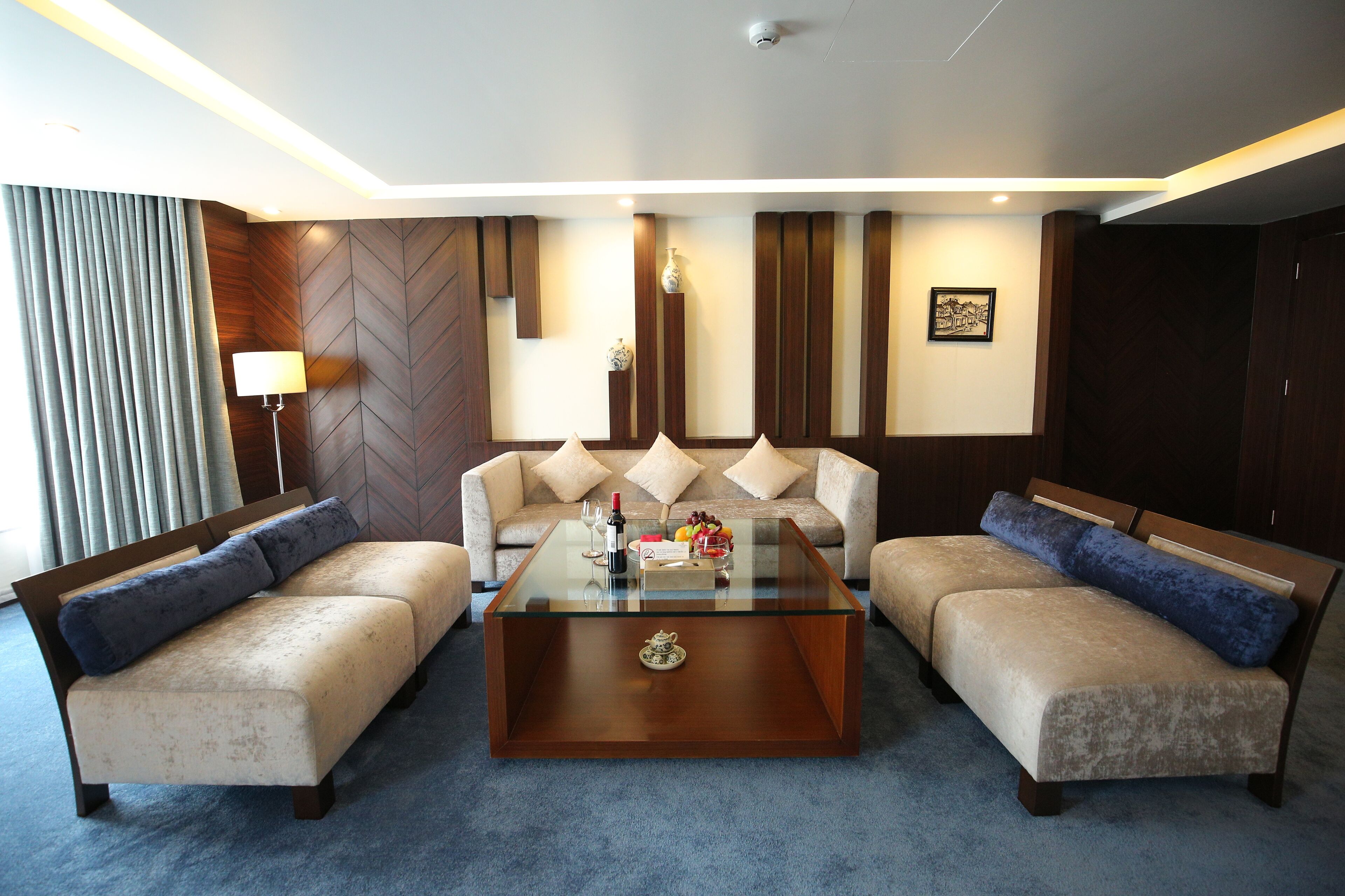 A modern living room with a glass-top coffee table, two sofas, a lamp, and a decorative vase.