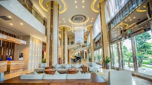 A spacious lobby with a central seating area, a staircase, and large windows offering views of the outdoors. - Central Luxury Ha Long Hotel (Bai Chay)