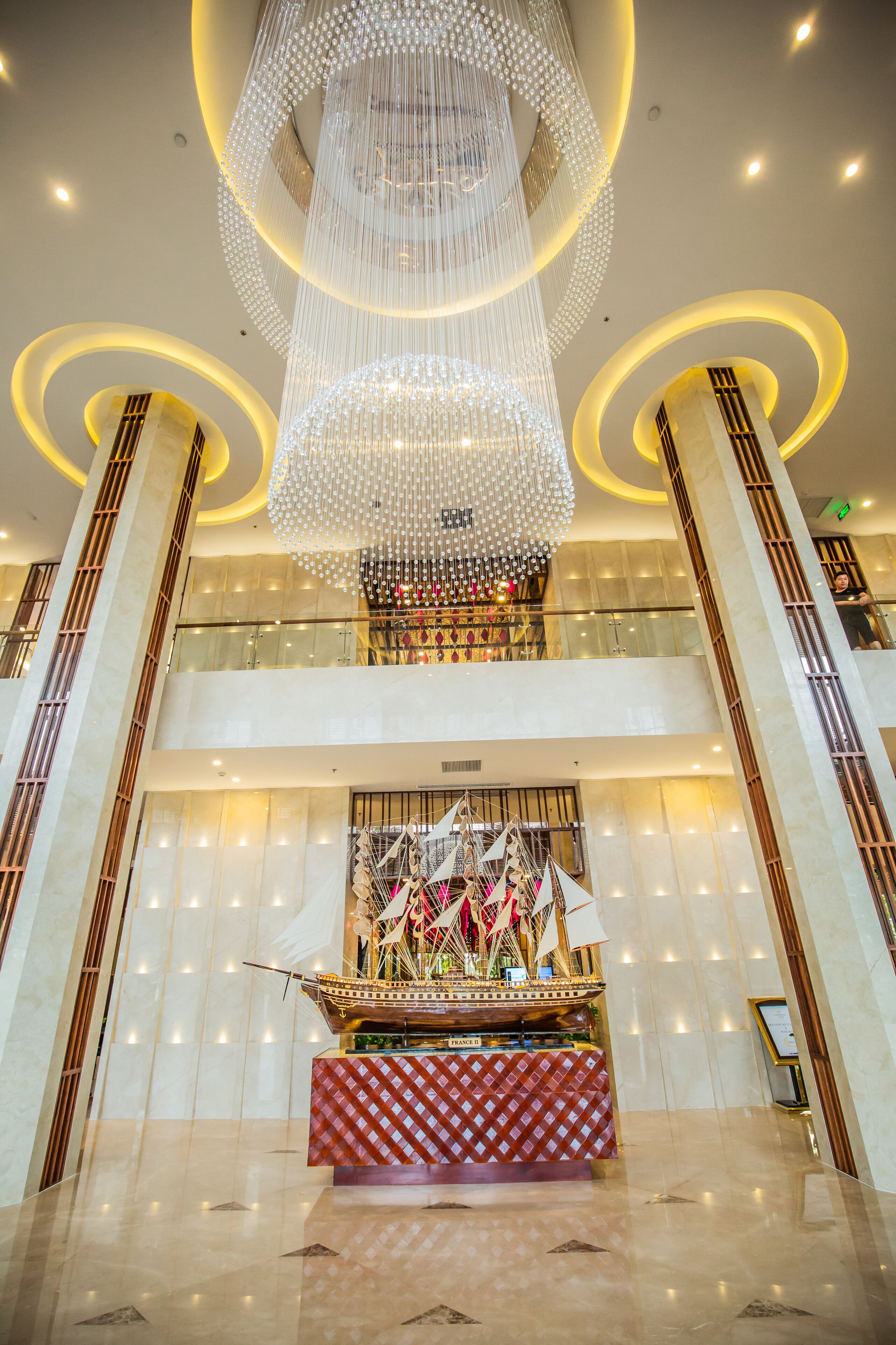 A grand lobby with a large chandelier, a central display of flags, and a checkered table.