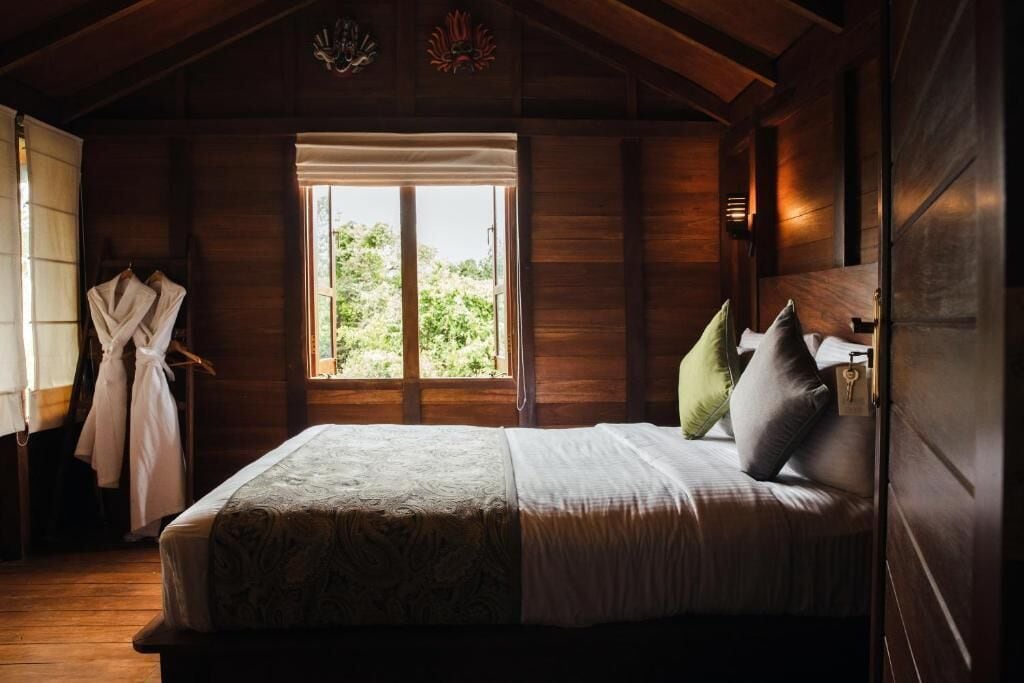 Une pièce en bois avec un lit, une fenêtre et un porte-manteau.