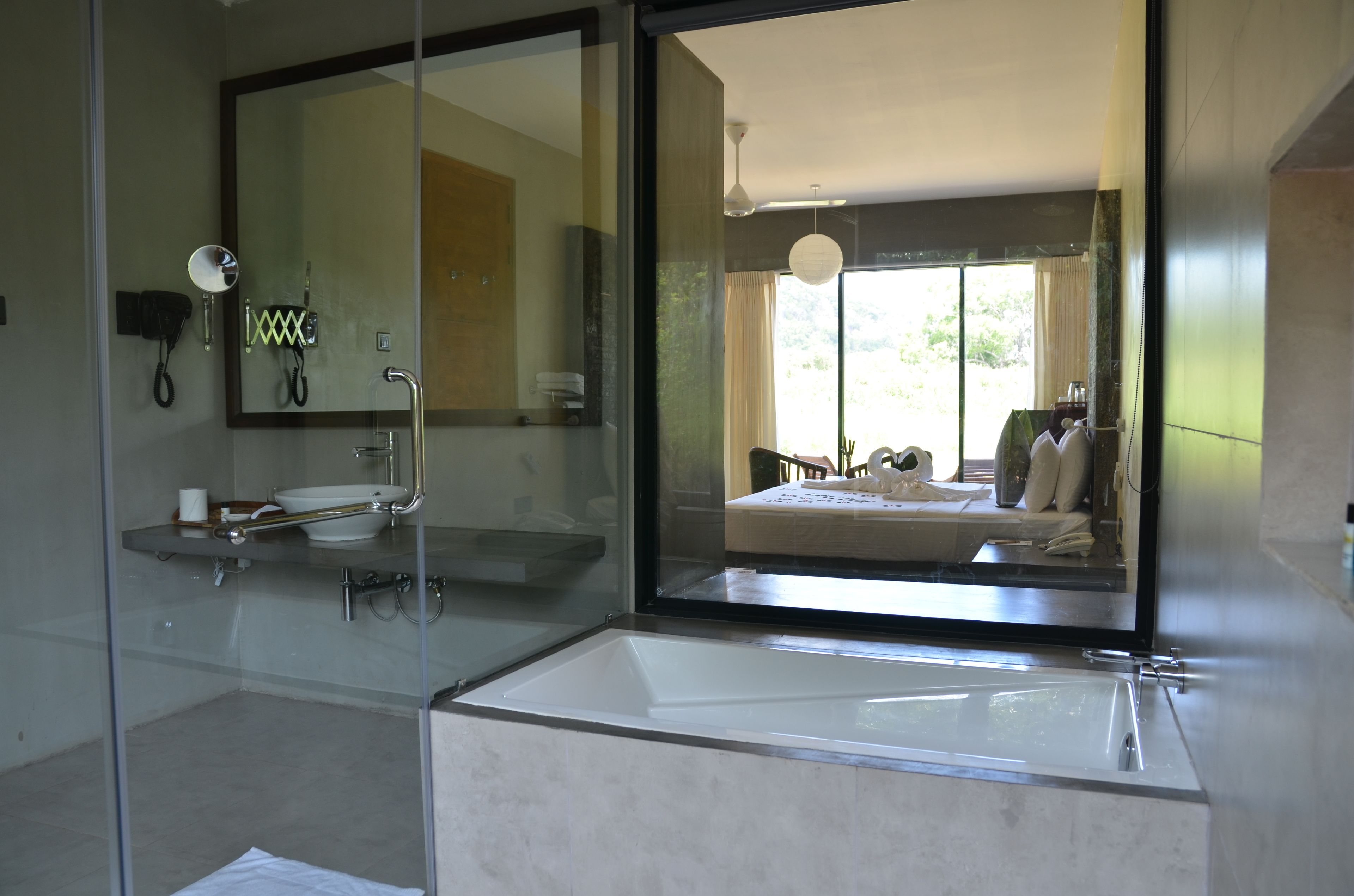 Un baño moderno con un espejo grande, cabina de ducha de vidrio y zona separada para el lavamanos.