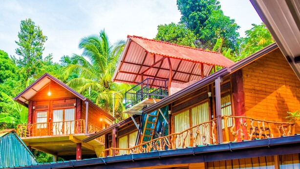 A wooden building with multiple balconies and a red roof, surrounded by lush greenery. - Ella City Reach Hostel (Ella)