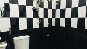 A bathroom with a black and white checkered tile pattern, a white toilet, and a shower with a handheld showerhead. - Ella City Reach Hostel (Ella)