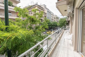Uma varanda com vista para uma rua arborizada e carros estacionados.