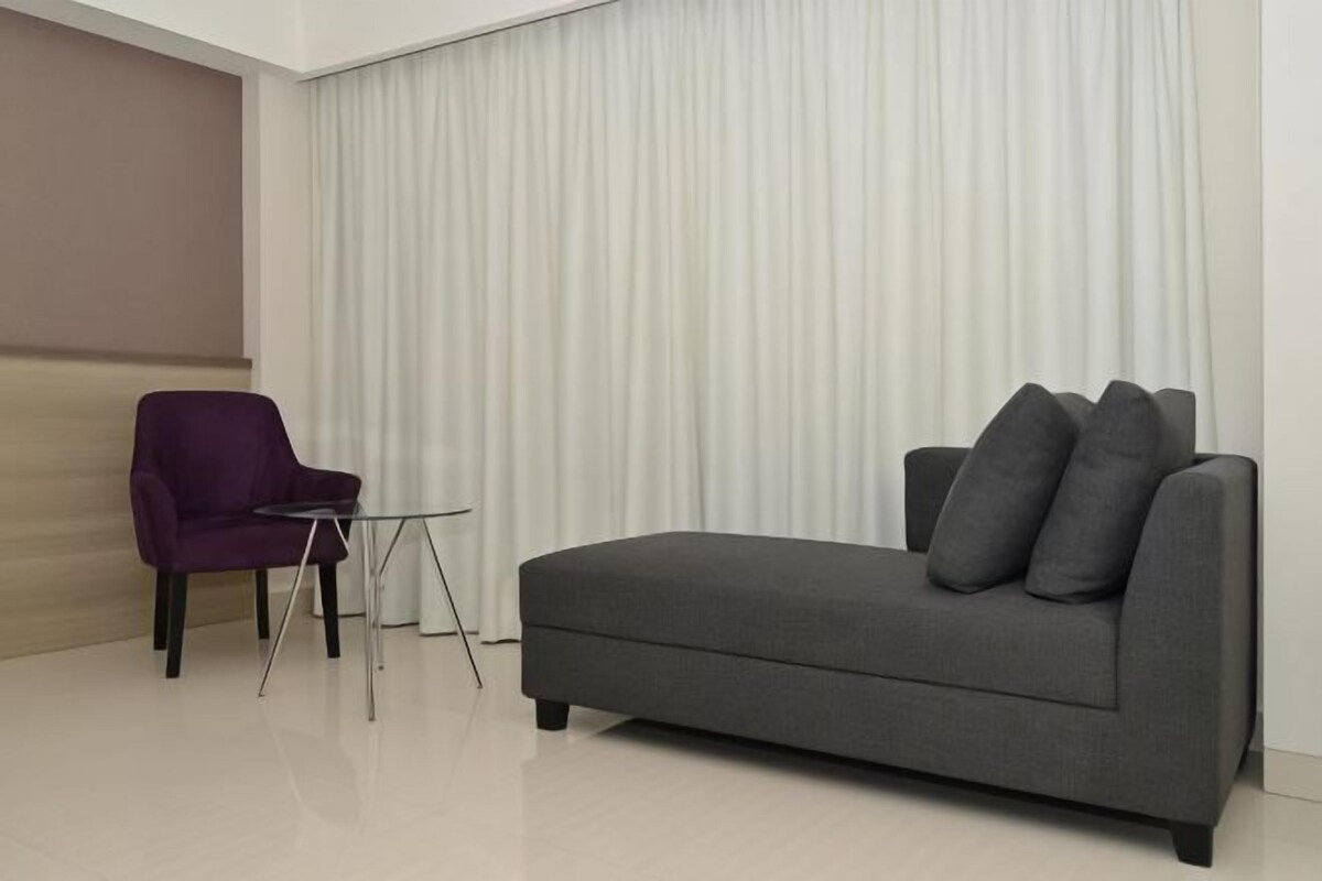 Un salon moderne avec un canapé gris, un fauteuil violet et une petite table en verre.