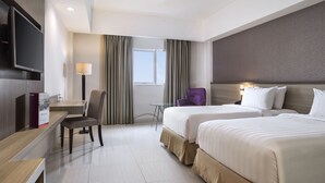 A hotel room with two beds, a desk, a chair, a TV, and a window with curtains.