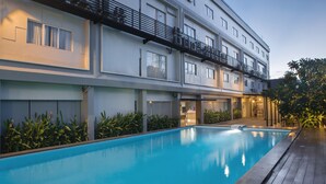A modern hotel with a swimming pool, balconies, and a well-maintained garden area.
