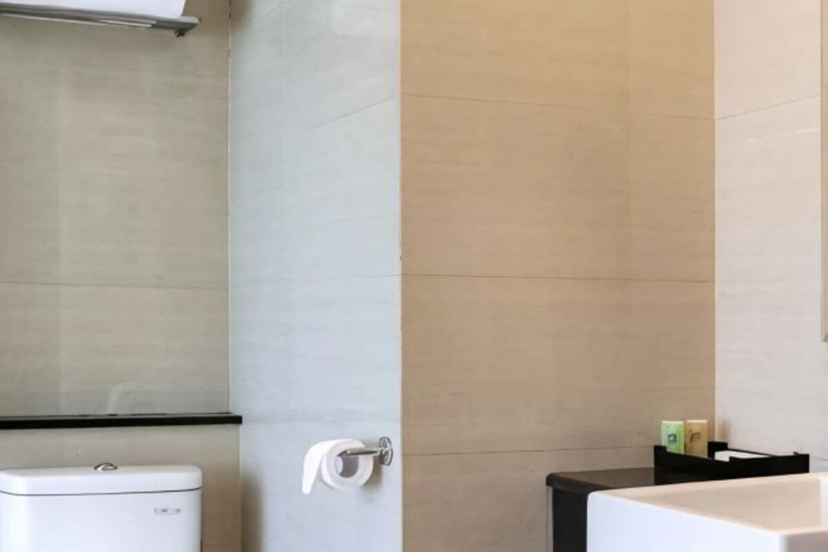 Une salle de bain équipée de toilettes, d’un distributeur de serviettes et d’un comptoir noir.