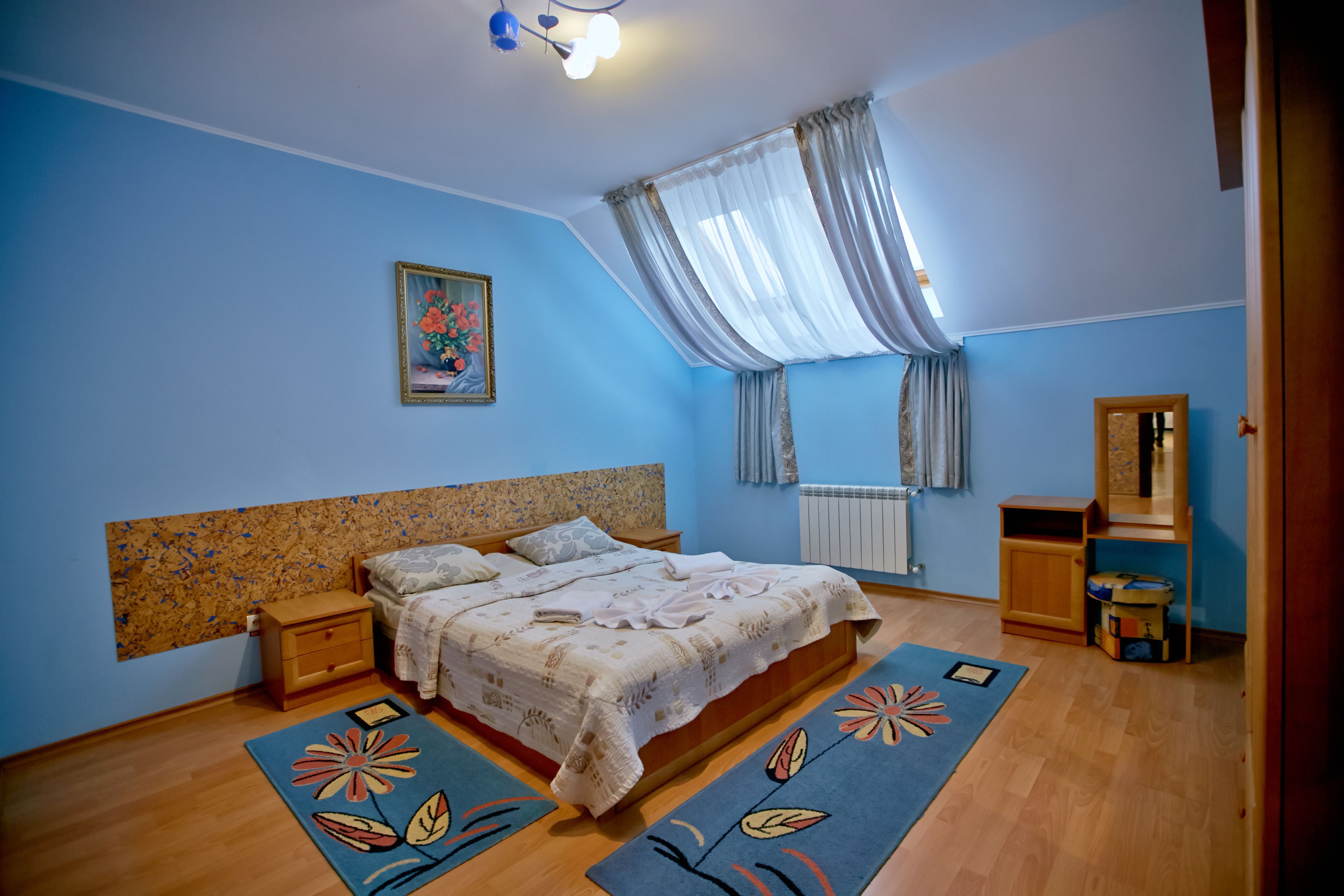 A bedroom with a bed, nightstands, a dresser, a mirror, and a window with curtains.