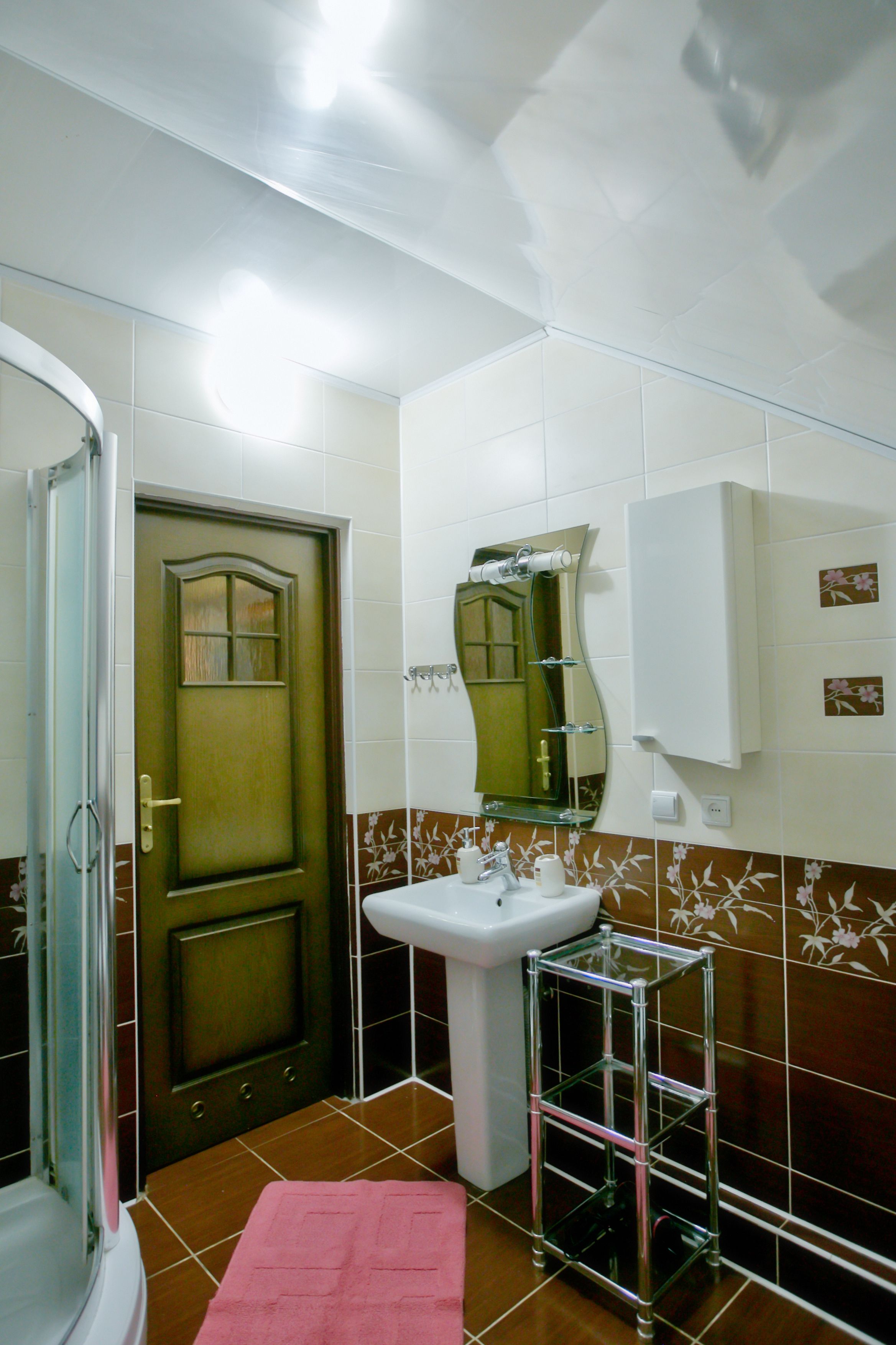 A bathroom with a shower, a sink, a mirror, and a towel rack.