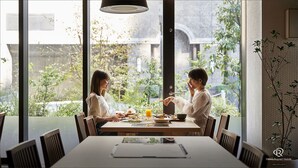 A dining area with a large window, a table with plates of food, and a person gesturing.