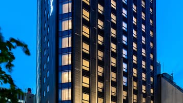 Un edificio moderno e slanciato, con facciata in vetro e finestre illuminate al crepuscolo.