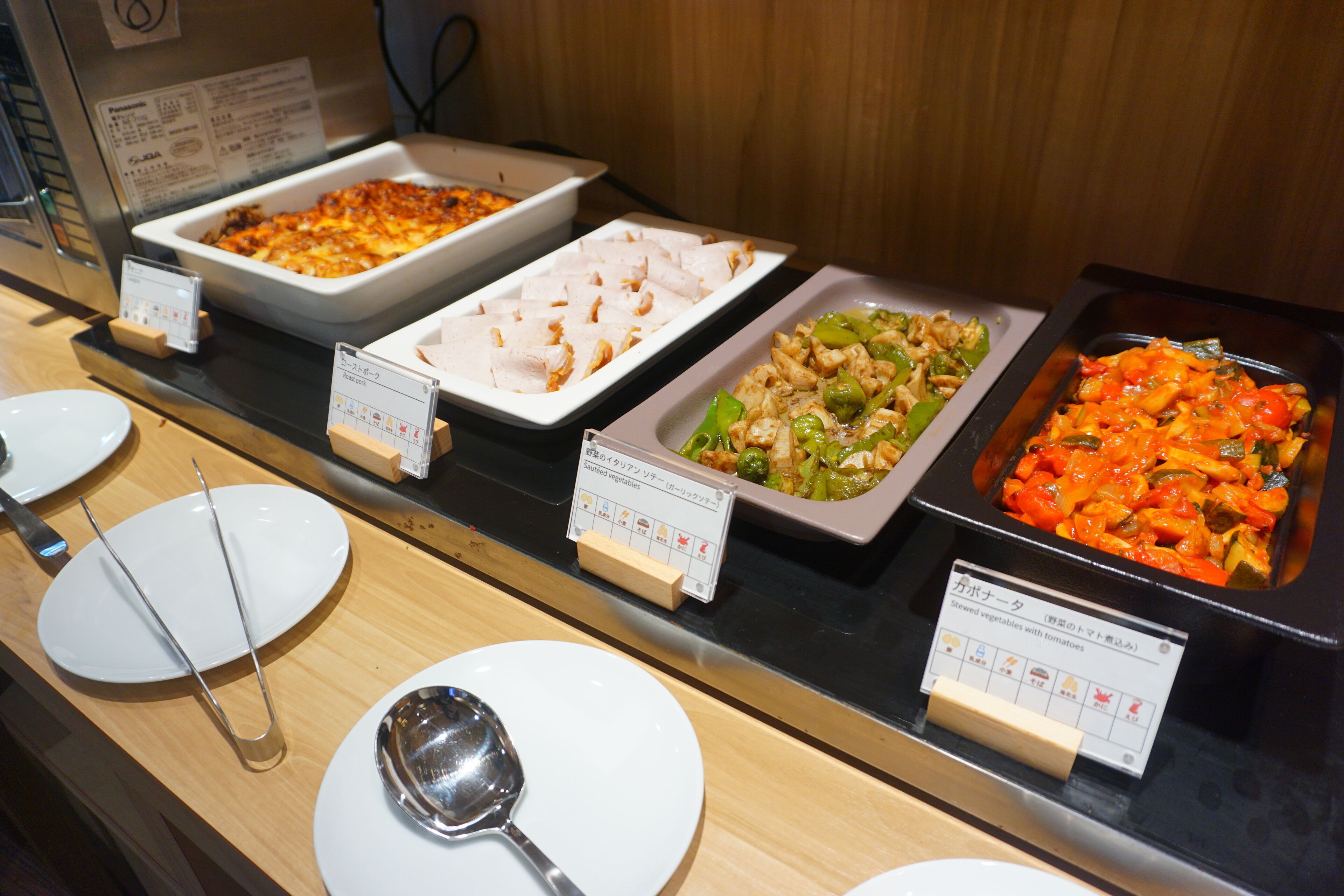 Un buffet proposant divers plats, notamment des pâtes, du poulet et des légumes.