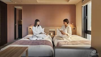 A hotel room with two beds, a wooden headboard, a bedside table, and a small clock.