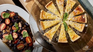 A pie with a lattice crust and a side salad with tomatoes and greens.