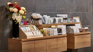A hotel reception desk with a variety of amenities including a tea station, coffee options, and a body wash towel display.