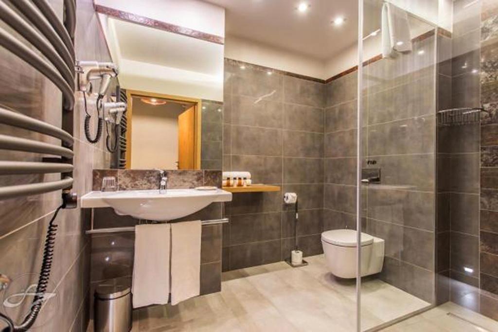 A modern bathroom with a glass-enclosed shower, a sink with a marble countertop, and a toilet.