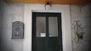 Una porta verde con un pannello di vetro satinato, una cassetta postale e una pianta fissata al muro.