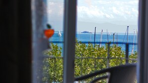 A view through a window with a sailboat on the water, a ship in the distance, and a clear sky. - Schiff am See (Konstanz)