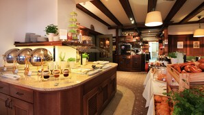 A kitchen with a central island, wooden cabinets, and a variety of food items displayed on the counter. - Schiff am See (Konstanz)