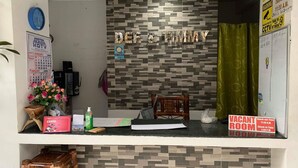 Un comptoir d’accueil avec une pancarte « DEF & TIMMY », un calendrier, une horloge, une pancarte « CHAMBRE LIBRE » et une pancarte « HEURE D’ARRIVÉE : 11h30 ».