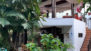 Un bâtiment moderne à l’extérieur blanc, doté d’un espace extérieur couvert et d’un escalier menant à un niveau supérieur.