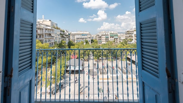 A balcony with a view of a cityscape, featuring multi-story buildings and a clear sky. - Victoria Majesty Apartments (Athens)