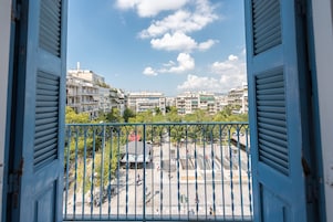 Uma varanda com vista para um horizonte urbano, mostrando edifícios altos e um céu claro.