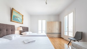 A hotel room with two beds, a wardrobe, a chair, and a painting on the wall. - Victoria Majesty Apartments (Athens)