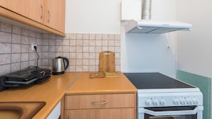A compact kitchen with a stove, a kettle, and a toaster. - Victoria Majesty Apartments (Athens)