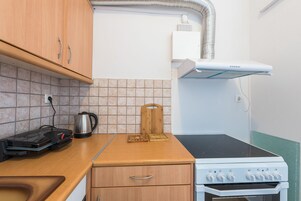 Cozinha compacta com fogão, chaleira e torradeira.