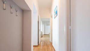 A narrow hallway with wooden flooring, white walls, and a door at the end leading to another room. - Victoria Majesty Apartments (Athens)