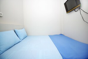 A single bed with blue bedding in a room with white walls. - Kamar Keluarga Syariah Johar Baru (Jakarta)