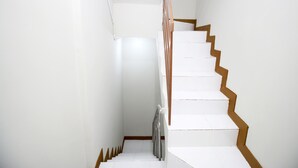 Een trap met witte treden en houten randen, leidend naar een plateau met een metalen leuning.