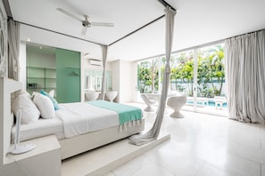 A modern bedroom with a large bed, a ceiling fan, and a view of a swimming pool. - Villa Puro Blanco (Canggu)