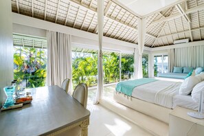 Una habitación con cama, una mesa de comedor y vistas a exuberante vegetación.