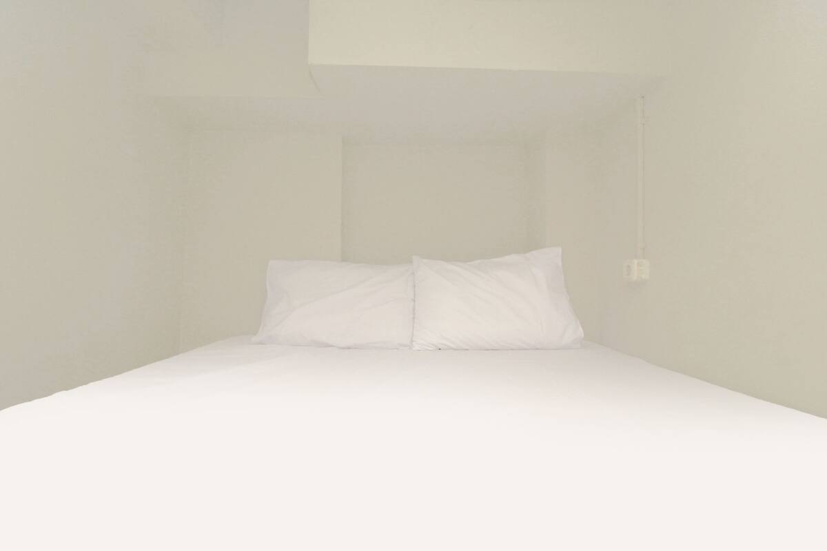 Ein schlichter, schlicht eingerichteter Raum mit einem Bett und einer einzelnen Lampe.
