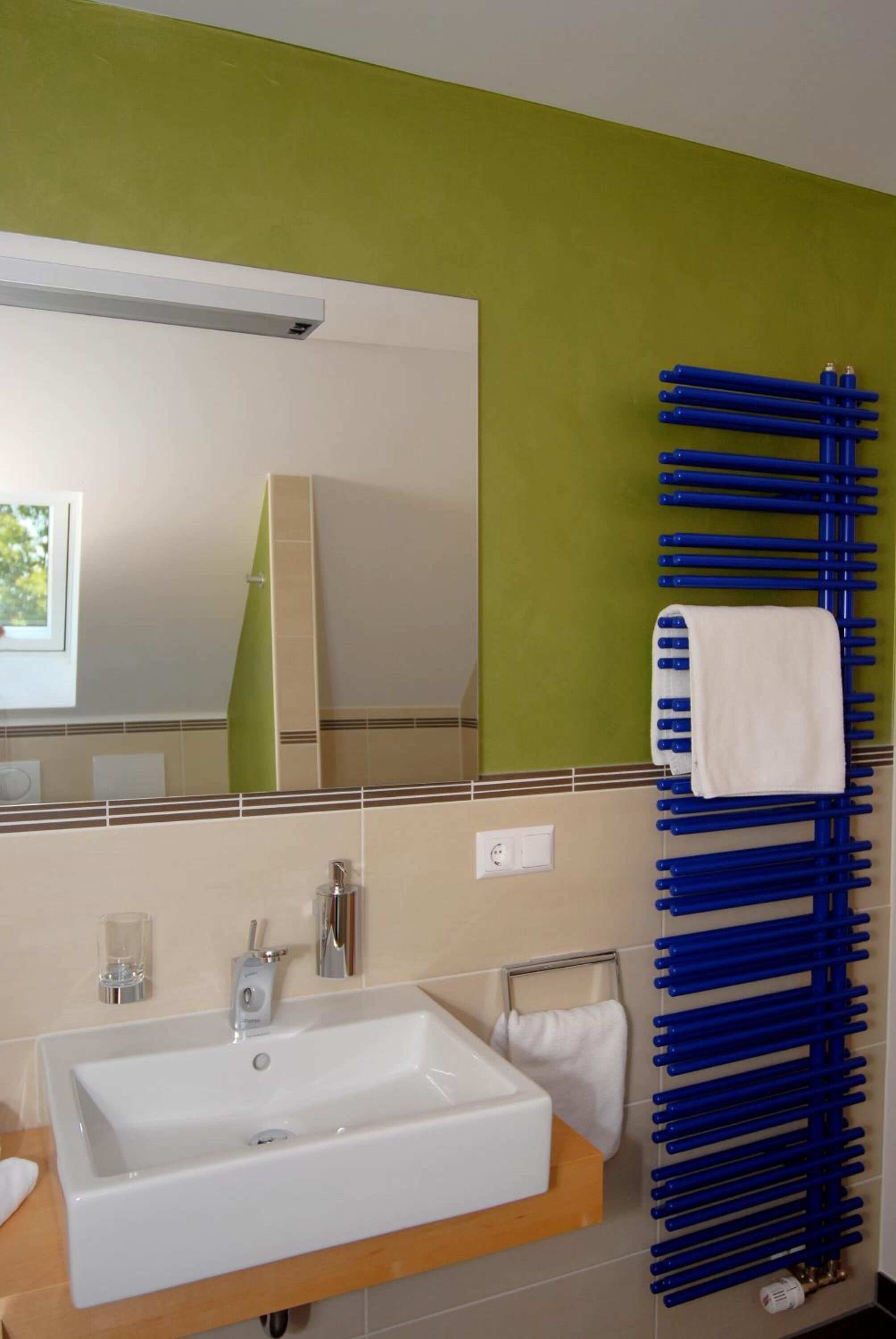 Une salle de bain avec un lavabo blanc, un miroir et un porte-serviettes bleu.