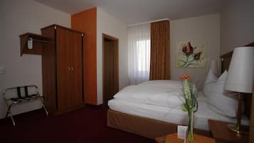 Ein Hotelzimmer mit Bett, Schreibtisch, Stuhl, Kleiderschrank und einem Bild an der Wand.