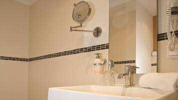 Un baño con un espejo grande, un lavabo blanco, una toalla y un taburete pequeño.