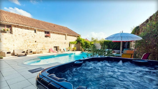 A hot tub with a stone building in the background. - Clos de la Gourmandière (Saint-Lothain)