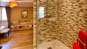 A modern bathroom with a glass shower enclosure, a red towel, and a wooden bench. - Clos de la Gourmandière (Saint-Lothain)