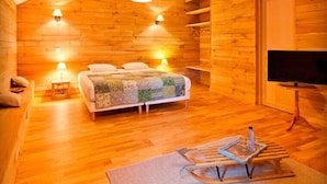 A cozy wooden cabin room with a bed, a TV, and a sled. - Clos de la Gourmandière (Saint-Lothain)