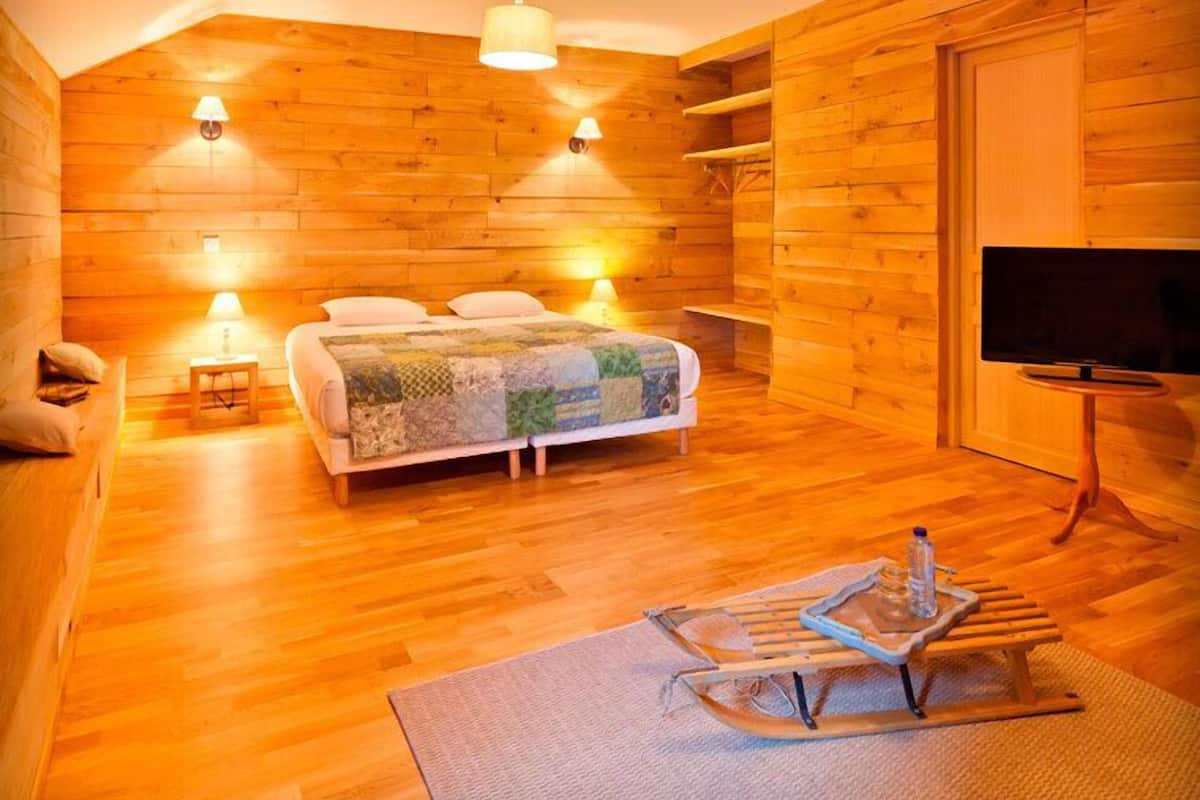 Een knus houten kamer met een bed, een televisie en een sled.