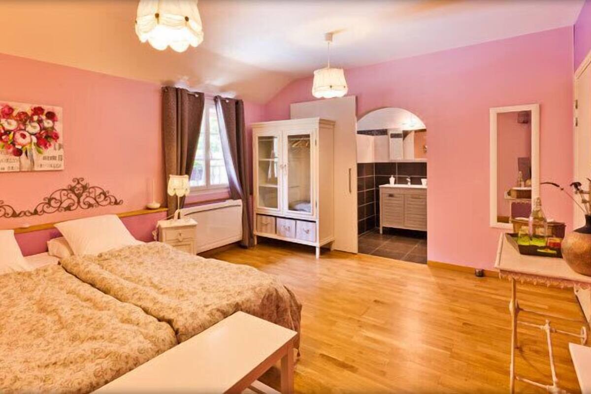 Een slaapkamer met een tweepersoonsbed, nachtkastje, kledingkast en spiegel.